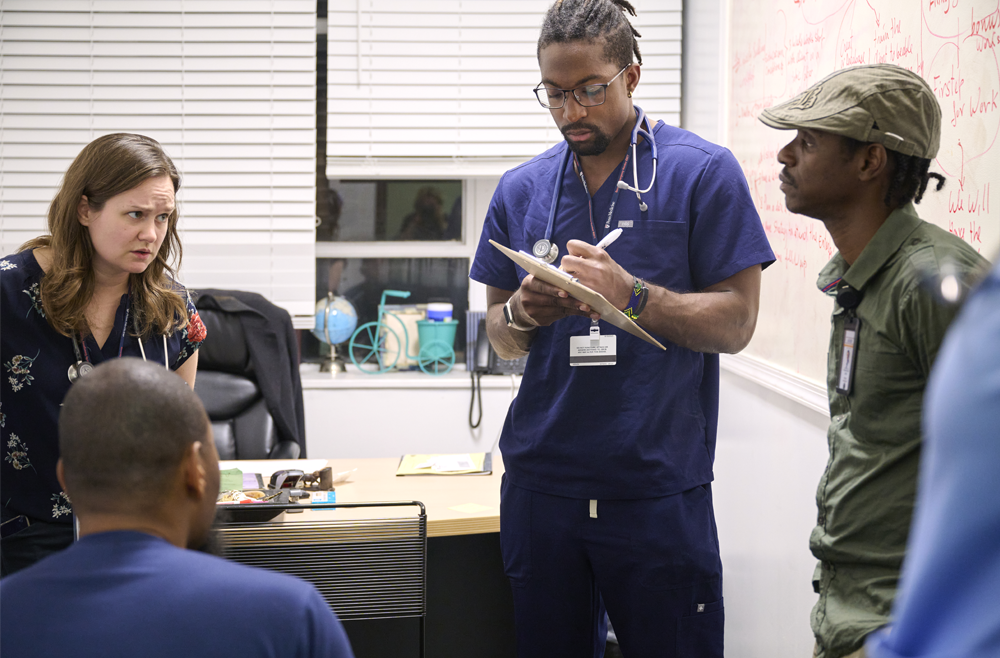 Members of Penn Medicine’s United Community Clinic at the African Family Health Organization gather for a meeting in an office.